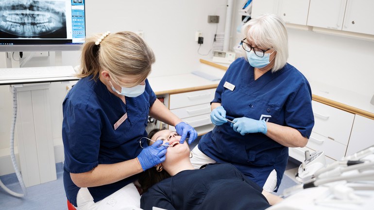 Tandläkare och assistent undersöker ungdomspatient på tandvårdskliniken.