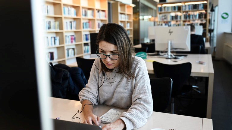 Student jobbar framför dator i universitetsbiblioteket.