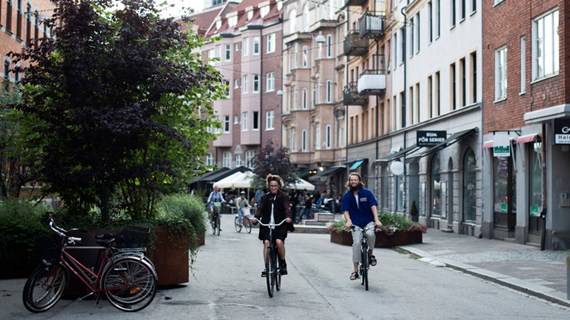Två personer cycklar fram i Malmömiljö mot kameran.