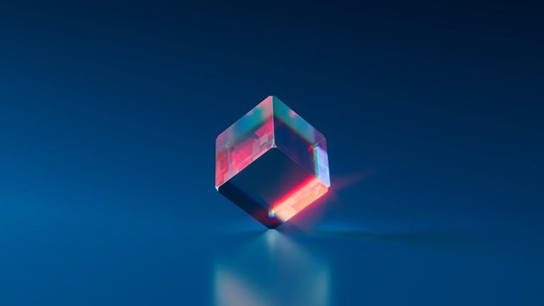 Genomskinlig kub som reflekterar ljus. Foto.