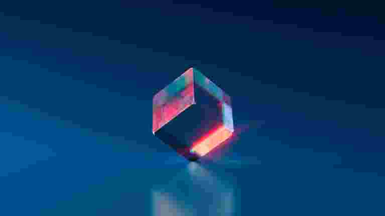 Genomskinlig kub som reflekterar ljus. Foto.