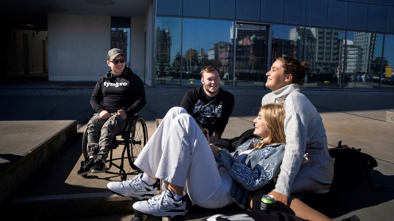 Studenter sitter utomhus i solen.