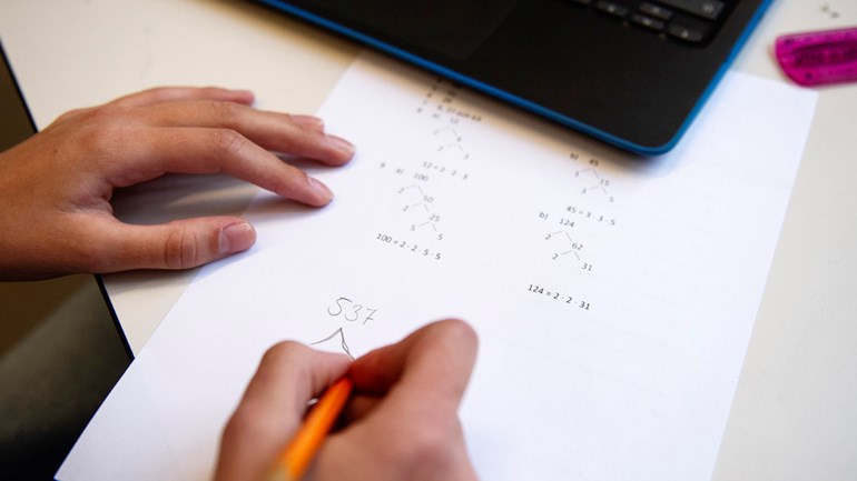 Närbild på hand och matematikövning.