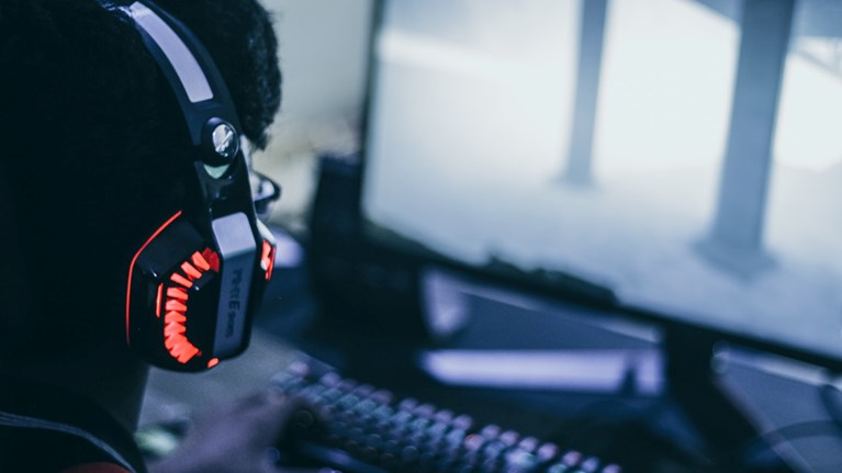 Person with headphones sitting in front of desktop computer.