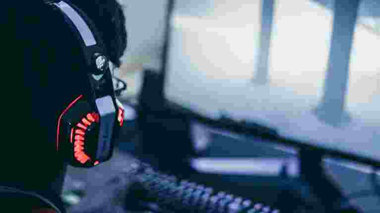 Person with headphones sitting in front of desktop computer.