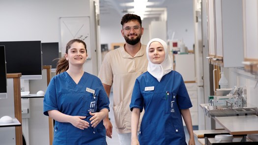 Människor i arbetskläder i universitetstandvårdens klinikmiljöer.