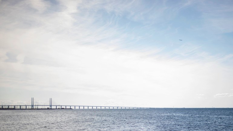 Människor badar i havet vid Ribersborg. I bakgrunden syns öresundsbron.