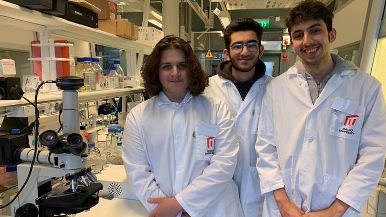 Tre gymnasieelever i ett laboratorium