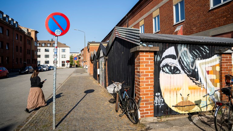 En person som går längs en gata bredvid en byggnad.