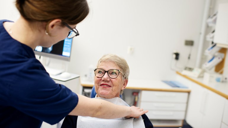 Tandvårdspersonal och äldre patient  i behandlingsrum på universitetets tandvårdsklinik. 