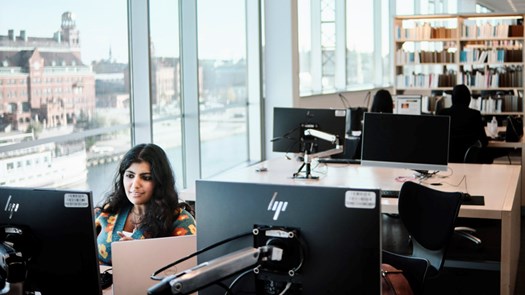 Student pluggar framför dator i biblioteket