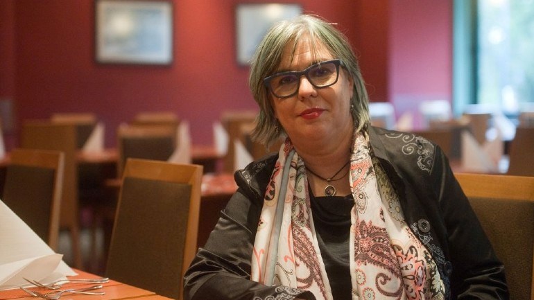 Andrea Pető sitting at a desk in an empty room