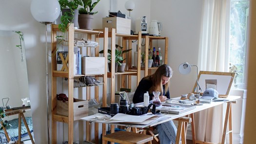 Student sitting behind a desk, painting.