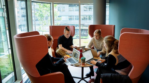 Fyra studenter pluggar tillsammans runt ett bord.