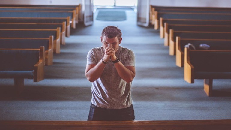 Man som ber i kyrka
