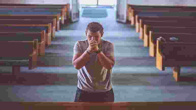 Man som ber i kyrka