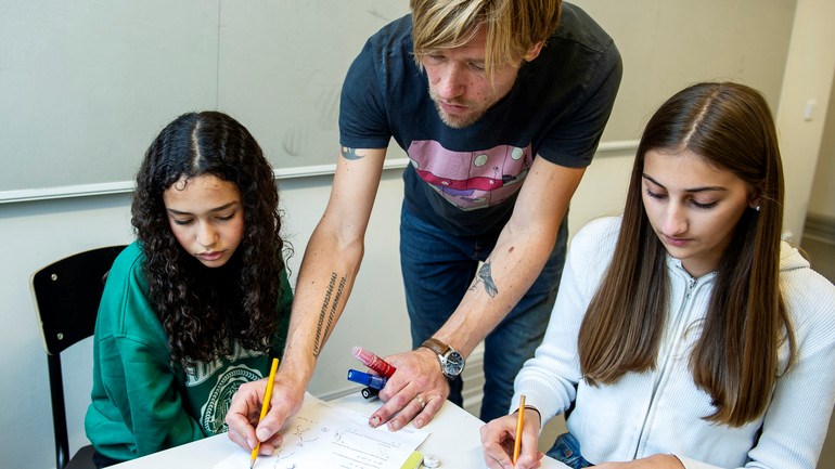 Lärare pratar med elev under lektion.