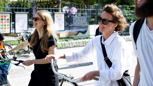 Tre personer promenerar med cyklar längst norra parkgatan.