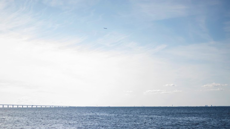 Människor badar i havet vid Ribersborg. I bakgrunden syns öresundsbron.