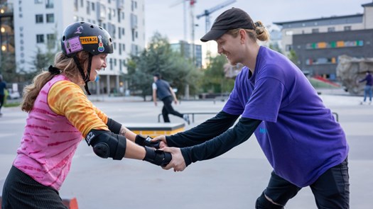 En person hjälper sin kompis åka rullskidskor i skatepark i västra hamnen.