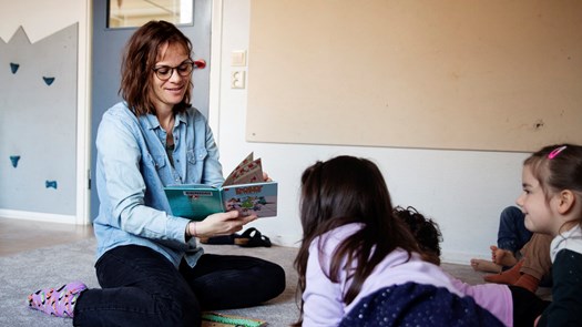 Pedagog på förskola läser högt ur bok.