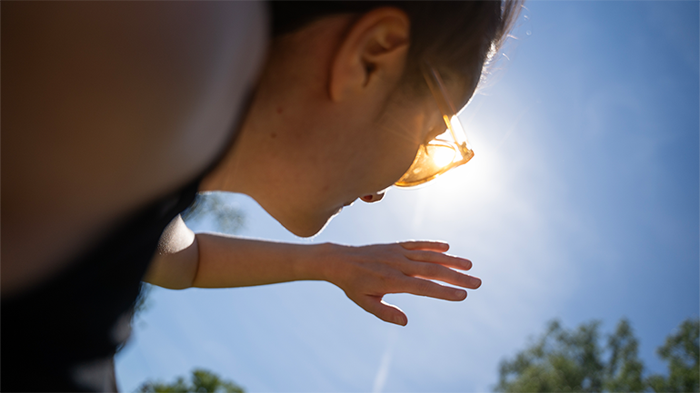 Kvinna som kisar mot solen